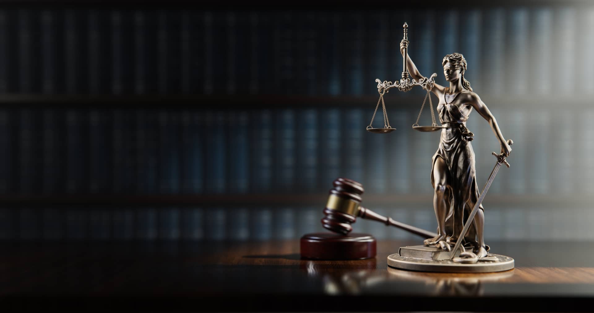 Silver Lady Justice statue with sword and scales beside a gavel in a law office