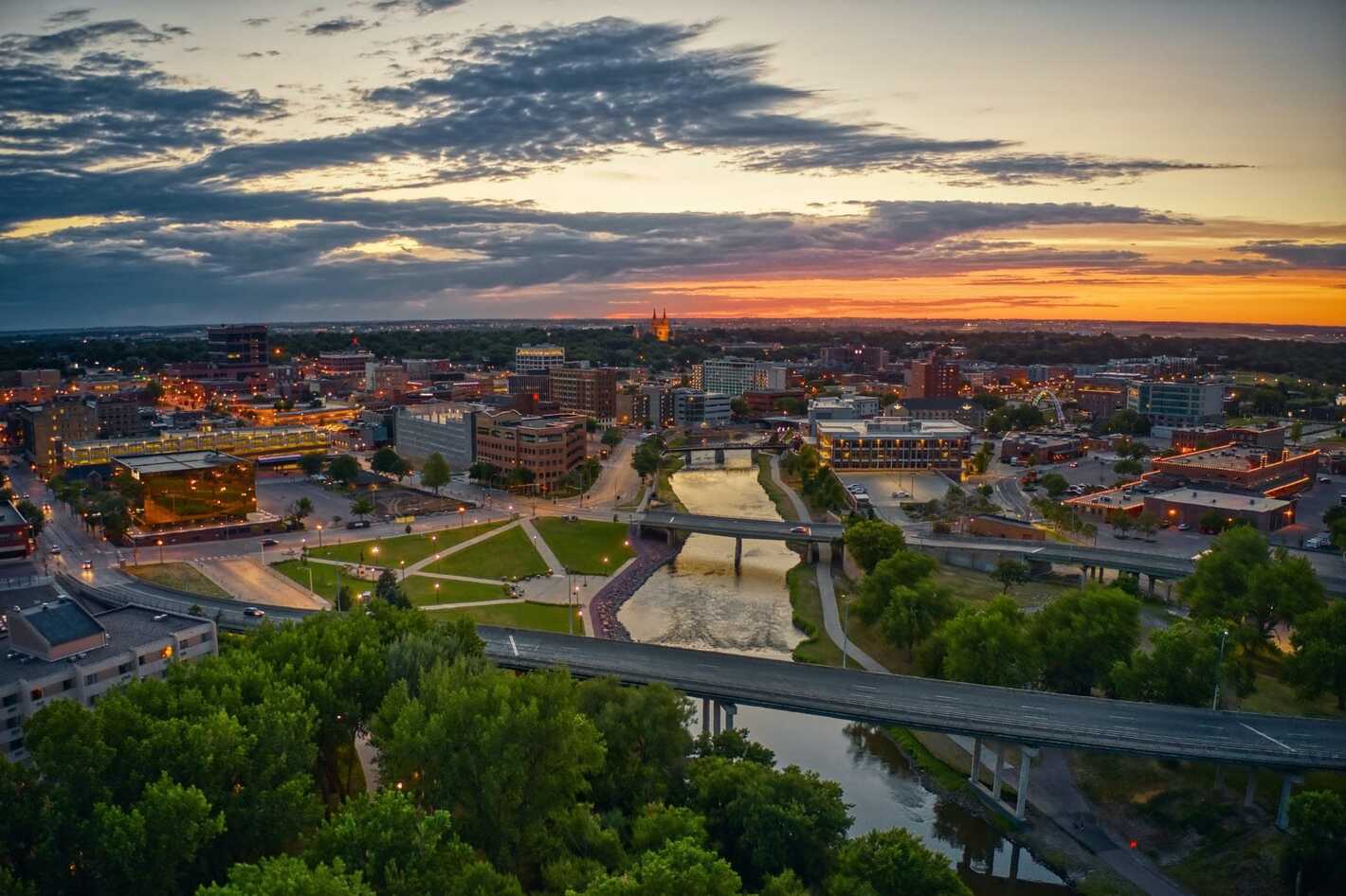 Aerial sunset view of downtown Sioux Falls with the river, a bridge, and city skyline