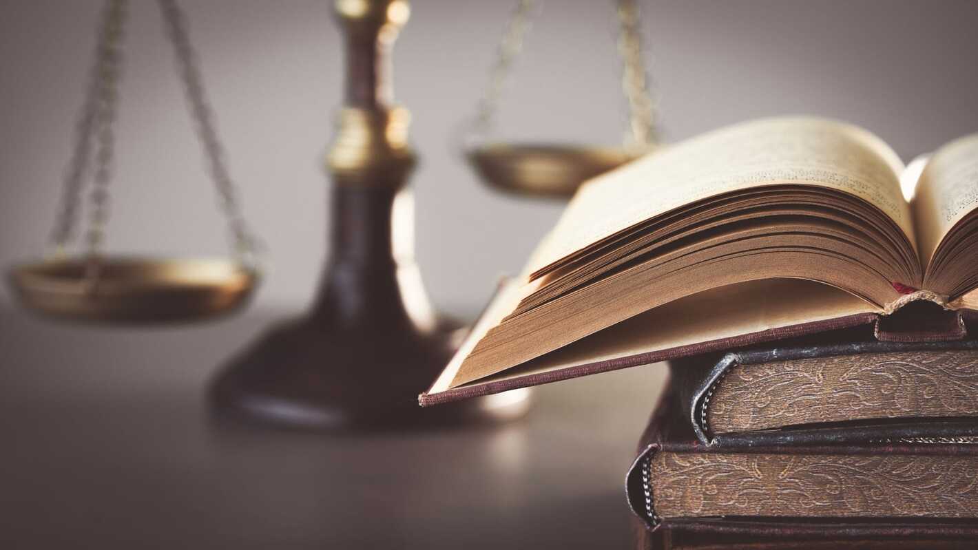 Bronze statuette of the scales of justice resting on an open antique law book